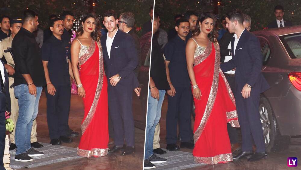 Priyanka in red saree with Nick in a navy blue suit. Priyanka in red saree with Nick in a navy blue suit.
