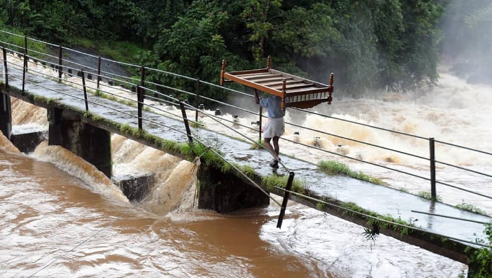 Man carrying his cot across a flooded river in Kerala Man carrying his cot across a flooded river in Kerala