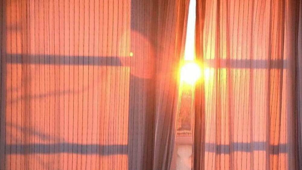 A sliver of coral sunlight through the curtains A sliver of coral sunlight through the curtains