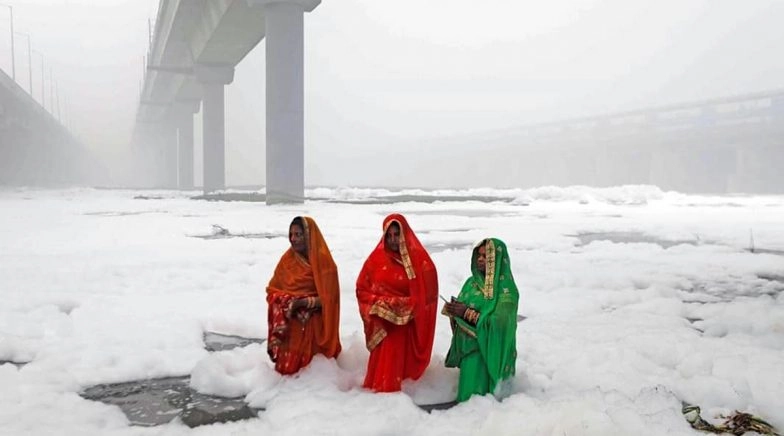 Chhath Puja devotees offer prayer amid toxic foams in the Yamuna river. 