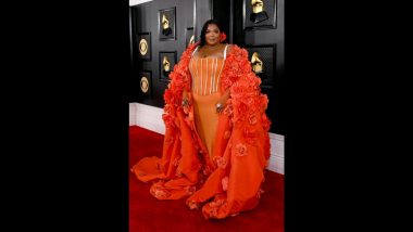 Grammys 2023: Lizzo Makes Grand Entrance at the Red Carpet in Orange Dress and Hooded Cape Adorned With Flowers (Watch Video)