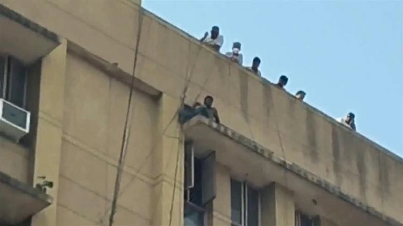 Delhi: Man Sits on Edge of Sanjay Gandhi Hospital Roof in Mangolpuri, Rescue Operation Underway (Watch Video)